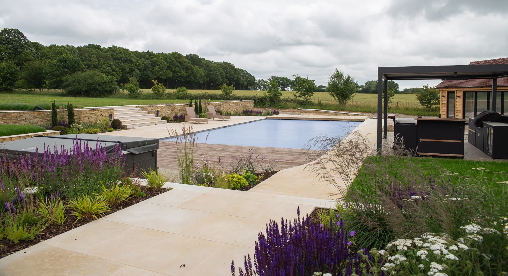 A wide stone poolside terrace with dry stone walling and planting