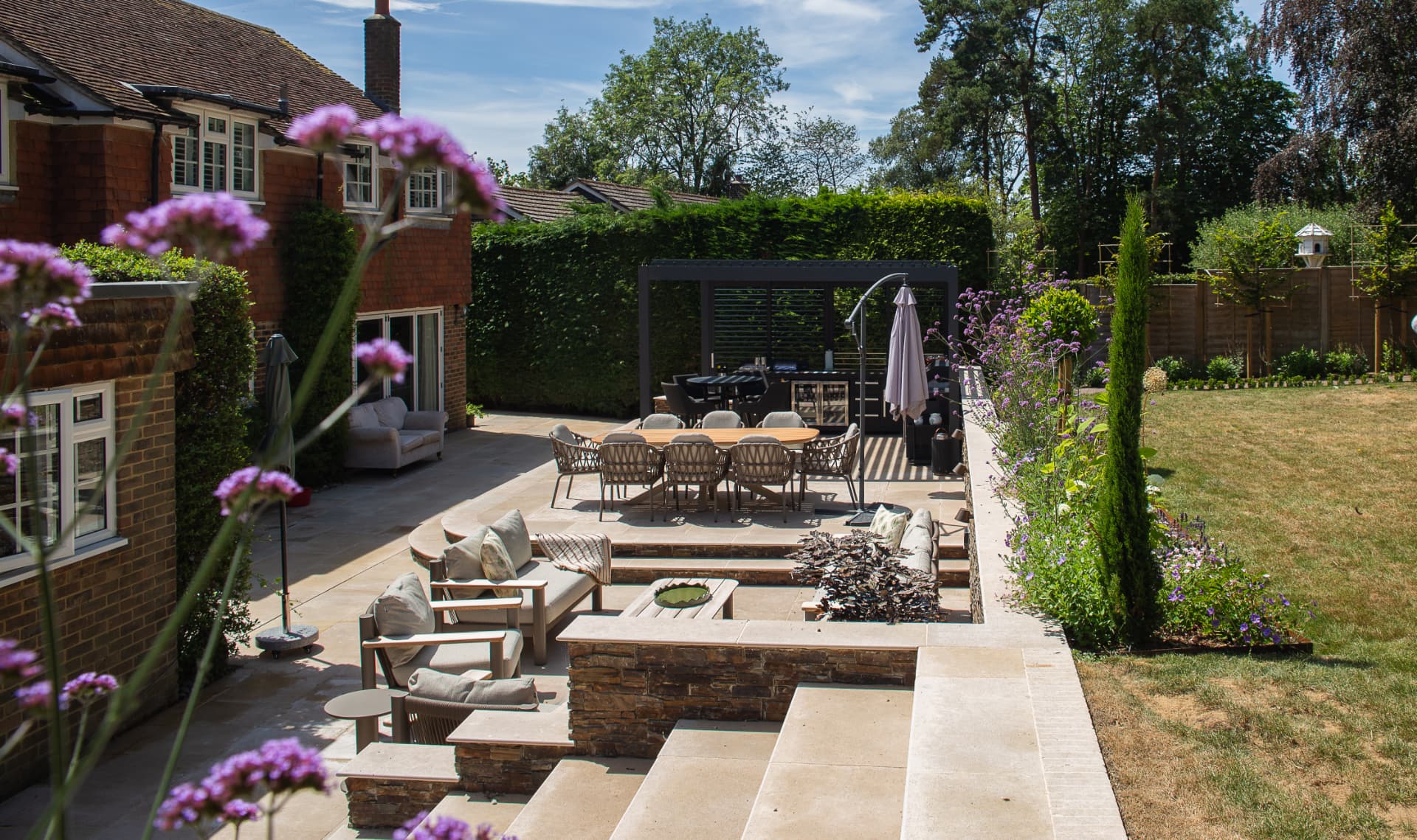 A sunken sandstone terrace with built-in seating, steps and a pergola dining area